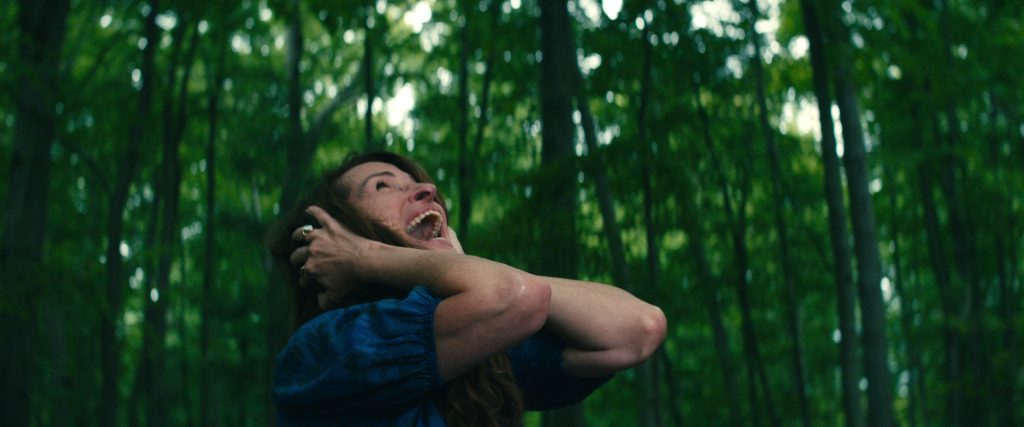 LEAVE THE WORLD BEHIND (2023) Julia Roberts as Amanda, screaming in the woods with her hands over her ears. CR: Courtesy NETFLIX