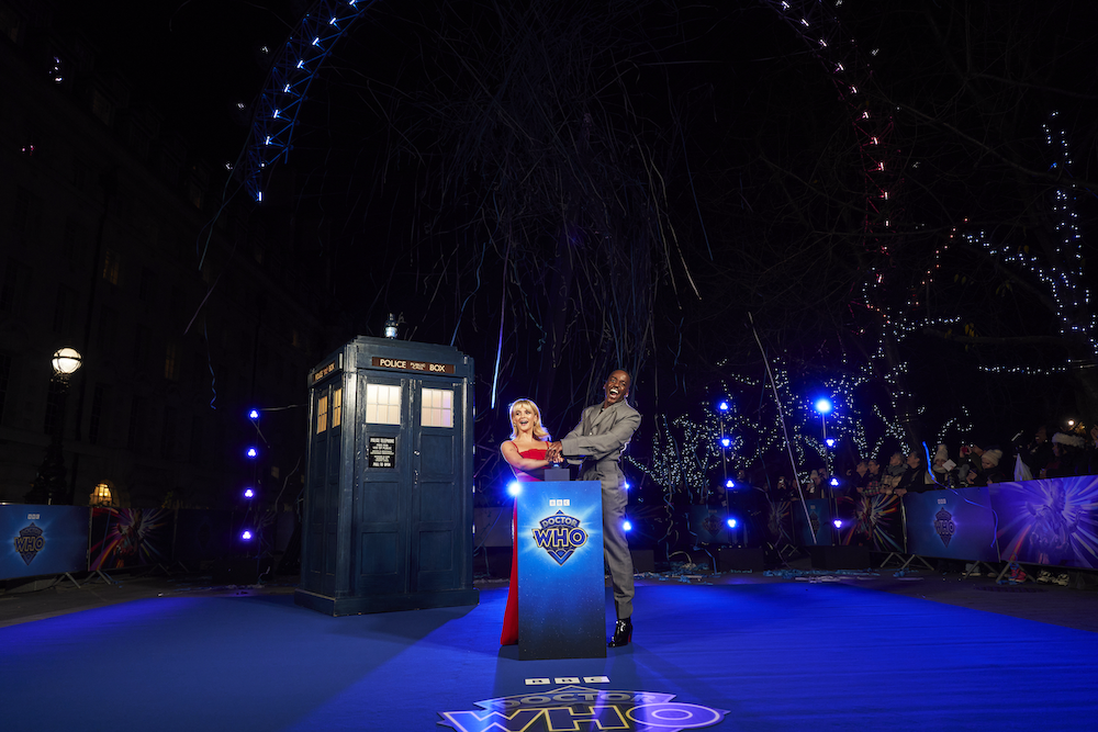 Millie Gibson and Ncuti Gatwa press a button to light up the London Eye in Doctor Who colors at the "Church on Ruby Road" blue carpet premiere